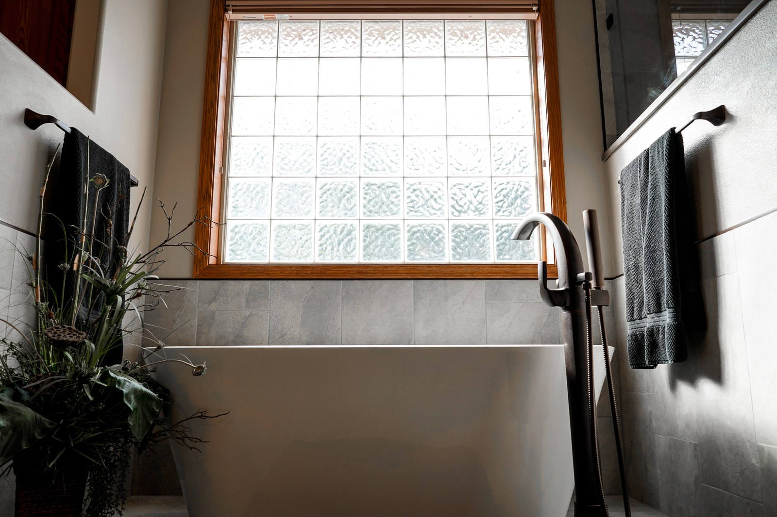 A remodeled bathroom with a freestanding soaking tub and glass block window