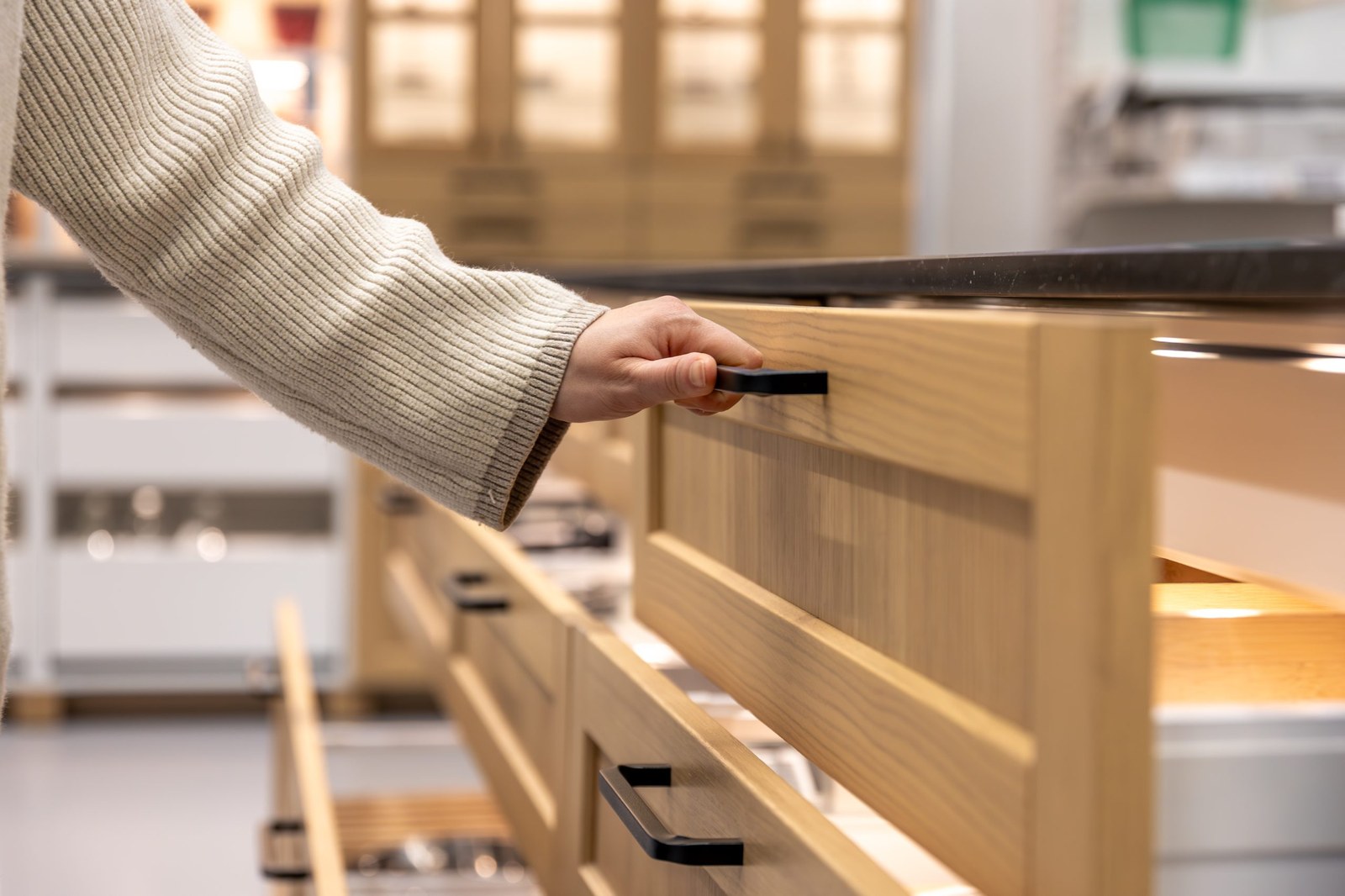 A hand opening a soft-close kitchen drawer in a Dwellings interior project