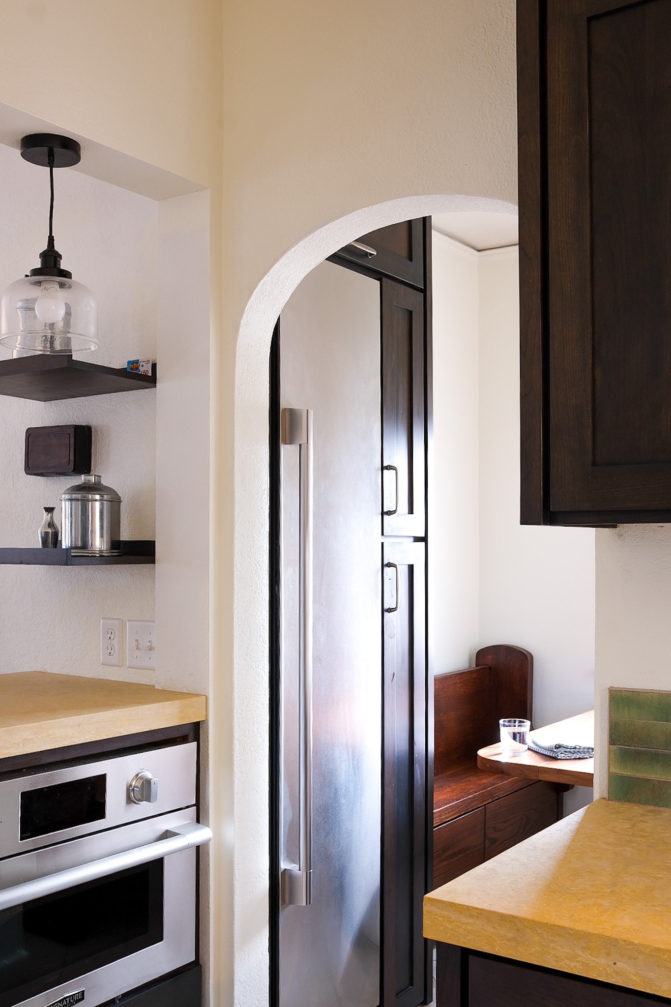 A Craftsman kitchen with an arched opening and stainless freezer column