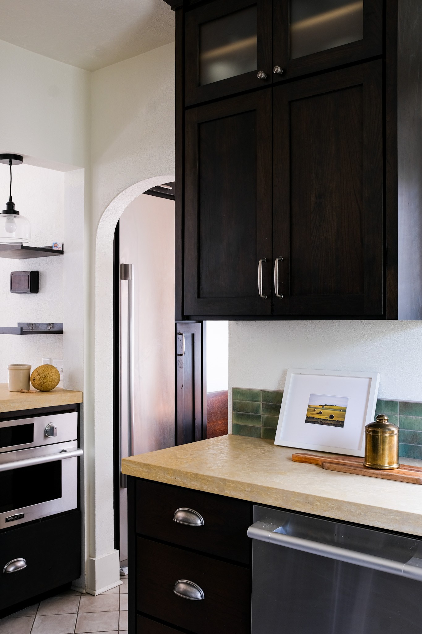 Espresso shaker cabinets with glass-front uppers and limestone countertops