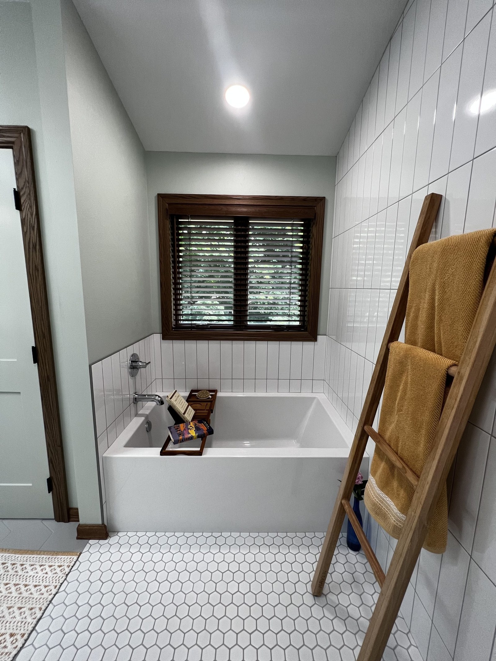 A remodeled bathroom with a built-in tub, white subway tile, and hexagon floor tile